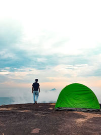 Rear view of man standing on land against sky