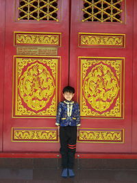 Full length of boy standing against closed door