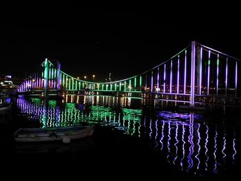 Illuminated bridge over river against sky at night