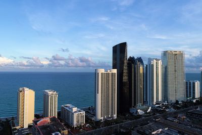 Modern buildings by sea against sky