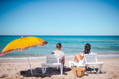 Rear view of people at beach against clear sky