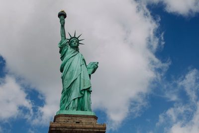 Low angle view of statue of liberty against cloudy sky