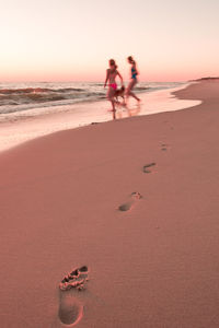 People on beach against sky during sunset