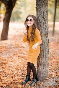 Cute smiling stylish child girl 4-5 year old wear yellow knit trendy dress and sun glasses outdoor
