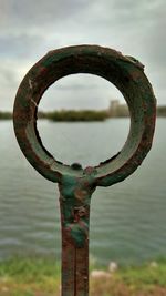 Close-up of metal structure in lake against sky