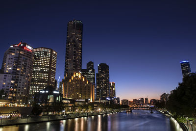 Illuminated buildings in city against sky at night