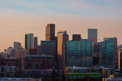 Modern buildings in city against sky during sunset