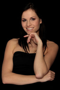 Portrait of a smiling young woman against black background