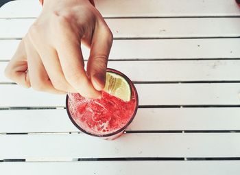 Cropped image of person hand with drink served on table