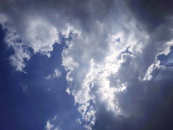 Low angle view of sunlight streaming through clouds