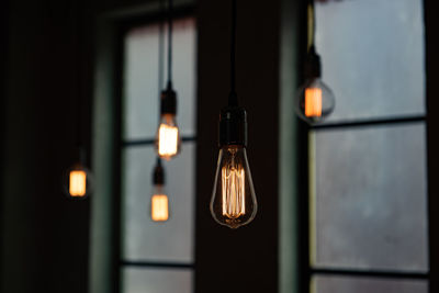 Close-up of illuminated pendant lights in darkroom