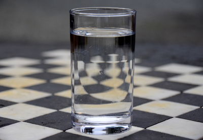 Close-up of water in glass on chess table. 