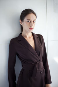 Portrait of young businesswoman standing against wall