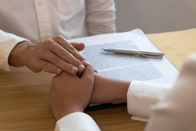 Midsection of couple holding hands on table