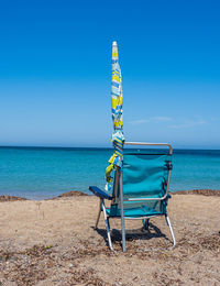 Deck chairs on beach against clear blue sky
