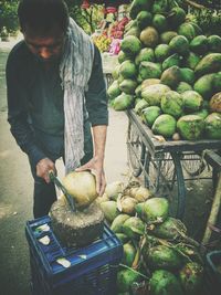 Vendor peeling coconuts at market stall