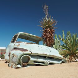 Abandoned old classic car half buried in sand of namib desert against clear blue sky