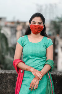 Portrait of beautiful young woman wearing mask at terrace