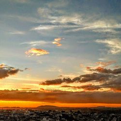 Scenic view of dramatic sky over city during sunset