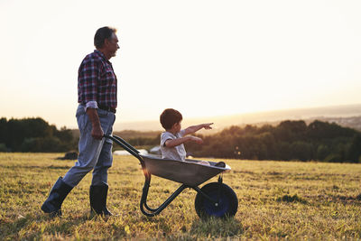 Father and son on field against sky