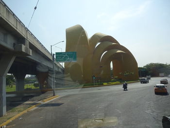 Vehicles on road against sky in city