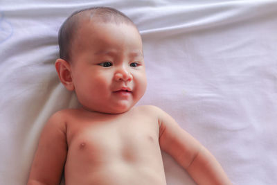 Portrait of cute baby lying on bed