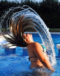Woman tossing her wet hair in swimming pool