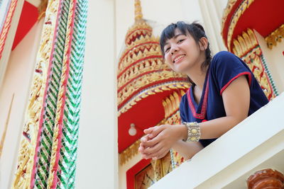 Low angle portrait of smiling young woman at temple