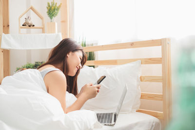 Young woman using mobile phone on bed