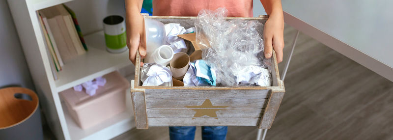 Girl showing a box of waste to recycle in ecology classroom