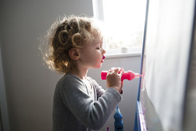 Side view of girl painting on whiteboard