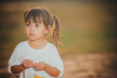 Cute girl looking away while standing outdoors