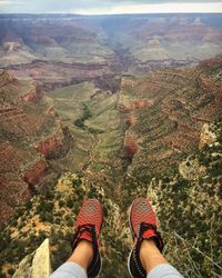 Low section of woman sitting against canyon