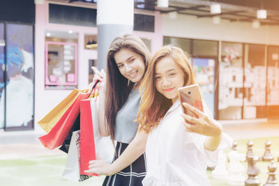 Young woman holding smart phone while standing in store