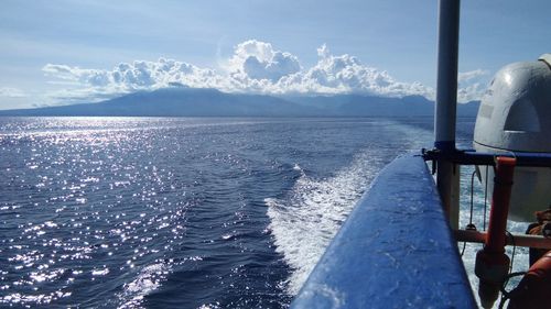 Sailboat sailing on sea by mountain against sky