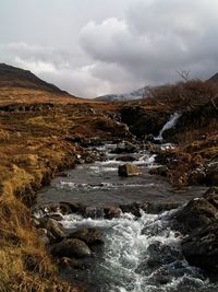 Scenic view of river against cloudy sky