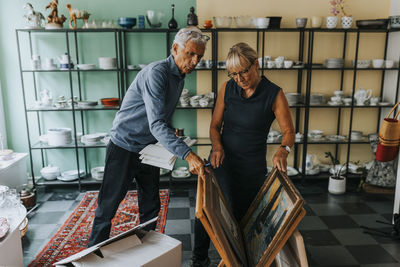 Elderly male and female entrepreneurs examining picture frames in antique shop