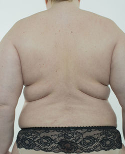 Rear view of shirtless young man against white background