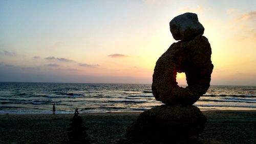 Silhouette statue by sea against sky during sunset