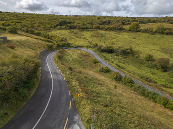 Empty road amidst landscape against sky