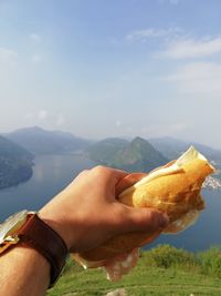 Midsection of man holding baguette against mountains