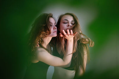 Close-up of beautiful women embracing against wall