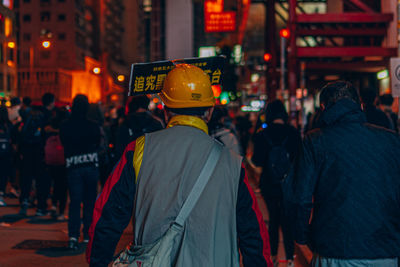 Rear view of people walking on city street at night