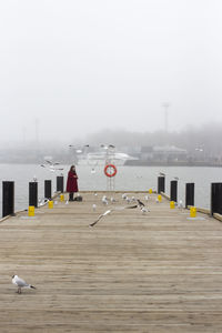 Man by lake against sky during winter