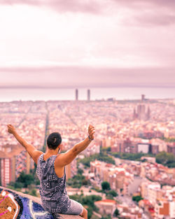 Rear view of man looking at cityscape against sky