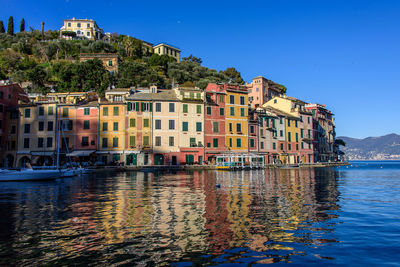 Buildings by houses against blue sky