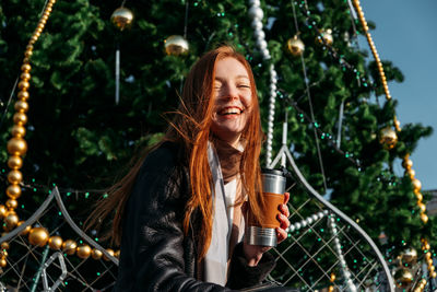 Portrait of smiling young woman against trees