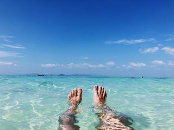 Low section of man in sea against blue sky during summer