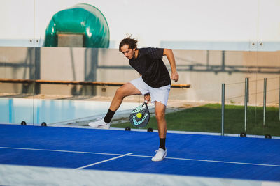 Full length of young woman exercising on court