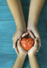 Cropped image of man holding heart shape on blue water